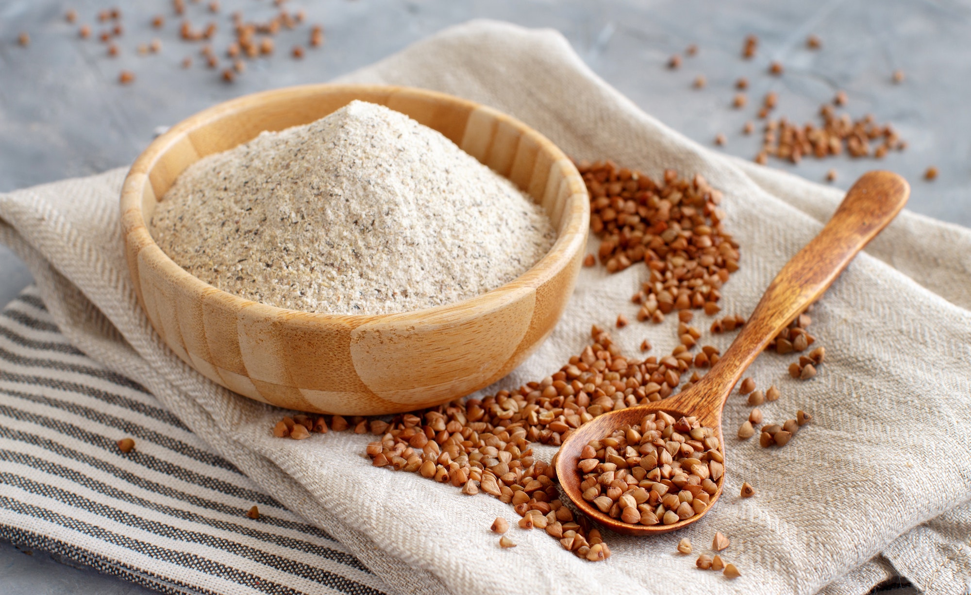 Buckwheat flour in a bowl and buckwheat grain in a spoon